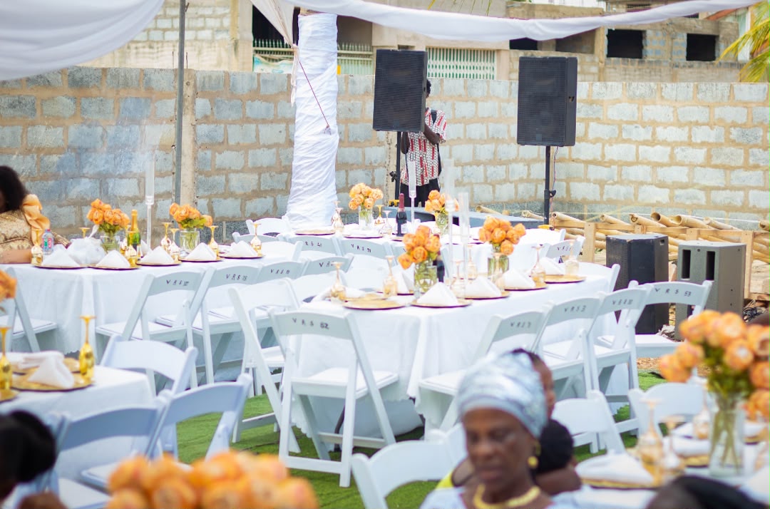 Outdoor white-chair reception with orange rose centerpieces